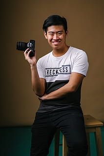 homem, sentado, banquinho, Câmera, pessoa, fotógrafo, retrato, vestem, uma pessoa, comprimento de três quartos, vista frontal, segurando, roupa casual, homens jovens, arma, dentro de casa, comunicação, de pé, adulto jovem, arma de fogo, homens, sorridente, olhando para a câmera, camiseta, tiro do estúdio, 5K, CC0, domínio público, royalty free