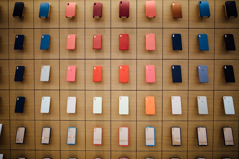 Sort-fargede iPhone-tilfeller, på rad, innendørs, full ramme, rekkefølge, stor gruppe gjenstander, ingen folk, gjentakelse, bakgrunn, nærbilde, kommunikasjon, side ved side, tekst, ordning, mønster, multi farget, organisasjon, overflod, variasjon, styre, 5K