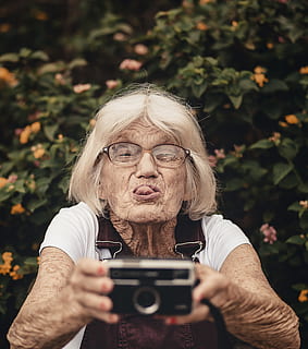 woman taking selfie, camera, close-up, elder, elderly, eyeglasses, facial expression, grey hair, hair, old age, pensioner, portrait, selfie, senior, woman, wrinkles, technology, photography themes, senior adult, one person, real people, lifestyles, holding, wireless technology, photographing, leisure activity, front view, adult, activity, camera - photographic equipment, day, women, outdoors, hairstyle, 2K, CC0, public domain, royalty free