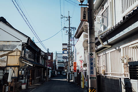 gray electric pole, city, street, town, urban, building, road, automobile, car, vehicle, transportation, alleyway, alley, metropolis, path, asphalt, tarmac, spoke, machine, wheel, alloy wheel, building exterior, architecture, built structure, cable, power line, electricity, day, sky, nature, residential district, the way forward, no people, direction, power supply, fuel and power generation, electricity pylon, outdoors, complexity, 5K, CC0, public domain, royalty free