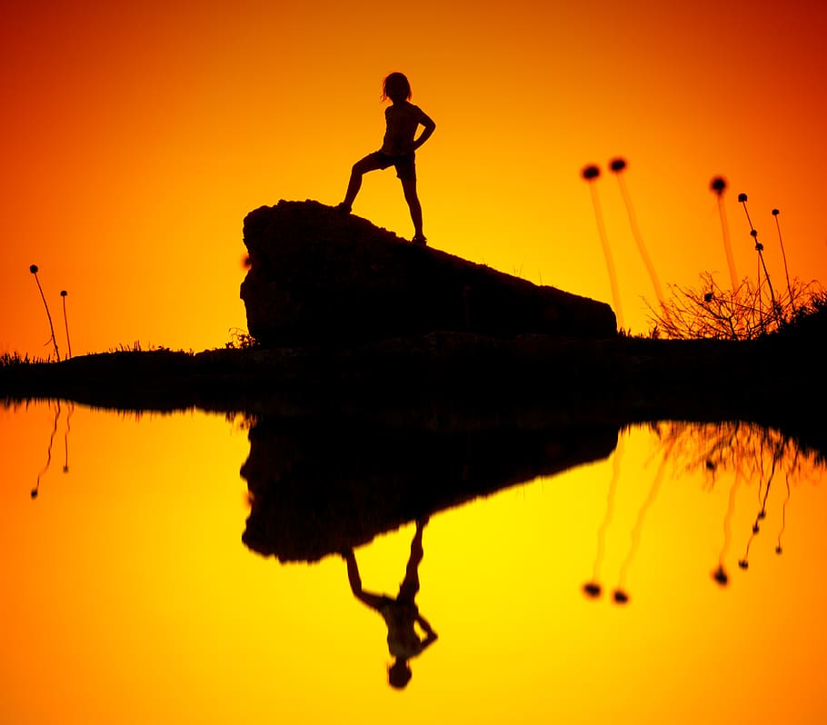 silueta, nen, de peu, rock, llum de fons, retroil·luminat, penya-segat, color, alba, tarda, herba, llac, paisatge, persona, pose, reflexió, escènic, sol, posta de sol, aigua, color taronja, cel, una persona, naturalesa, bellesa a la natura, homes, tranquil·litat, aigua estancada, longitud completa, davant del mar, escenics - natura, simetria, 4K
