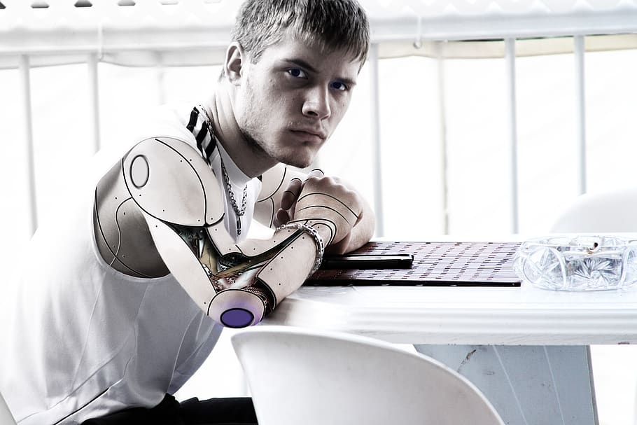 homme, acier, artificiel, bras, séance, de face, blanc, table, fâché, intelligence artificielle, équipement, futuriste, Humain, intelligence, machine, apprentissage automatique, machinerie, mâle, mécanique, métal, modèle, la personne, robot, science, La technologie, virtuel, une personne, portrait, à l'intérieur, Hommes, mâles, ordinateur, confiance, jeune adulte, Technologie sans fil, regarder la caméra, portable, photo du visage, enfant, émotion, Vrais gens, utilisant un ordinateur portable, contemplation, clavier, 5K