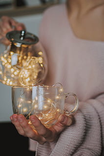 yellow string light, holding, one person, human hand, hand, human body part, midsection, close-up, indoors, glass, real people, drink, focus on foreground, refreshment, adult, food and drink, women, transparent, glass - material, drinking glass, tea cup, finger, 5K, CC0, public domain, royalty free