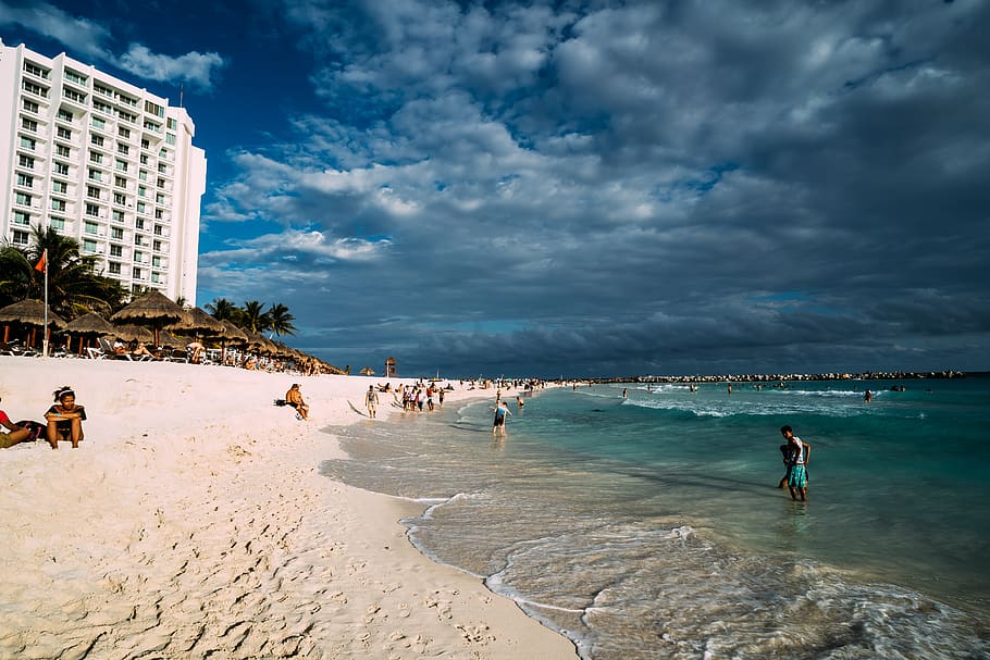 foto, gent, vora del mar, platja, edifici, núvols, ennuvolat, diversió, medi ambient, idíl·lic, oci, naturalesa, oceà, costa d’oceà, recreació, sorra, paisatge, escènic, mar, paisatge marí, Riba, cel, estiu, navega, vacances, aigua, terra, núvol - cel, grup de persones, persones reals, arquitectura, estructura construïda, homes, exterior de l'edifici, gran grup de persones, multitud, dia, estils de vida, activitat d'oci, a l'aire lliure, 5K