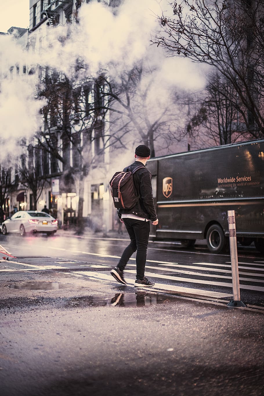mand krydser vejen, beklædning, fodtøj, sko, tøj, person, vej, transportmidler, køretøj, lastbil, human, asfalt, bil, automobil, new york, fodgænger, frakke, taske, pyt, hjul, en person, fuld længde, træ, rigtige mennesker, by, transportform, herrer, gå, gade, bagfra, arkitektur, livsstil, dag, plante, byliv, stående, natur, udendørs, varme tøj, 2K
