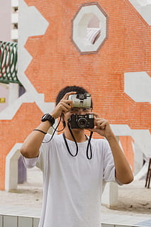 Person, Mensch, Kamera, Elektronik, Fotografie, Foto, Porträt, Fotograf, Spielplatz, alte Schule, Singapur, Produkt-Shooting, Gesicht, Ärmel, bekleidung, Kleidung, Menschen, Wand, kurze Hose, Gurt, Kamera - Fotoausrüstung, Fotografie-Themen, Technologie, Fotografieren, eine Person, Aktivität, echte Menschen, Lebensstile, Vorderansicht, Freizeitbeschäftigung, halten, die Architektur, Taille hoch, Fotoausrüstung, Legere Kleidung, Wandbau - Funktion, Stehen, gebaute Struktur, Digitalkamera, draußen, verdecktes Gesicht, 5K, CC0, gemeinfrei, lizenzfrei